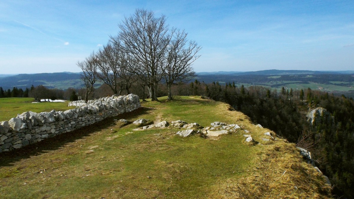 Sentier de crête du Creux du Van, entre un muret de pierres et l'abrupt rocheux.