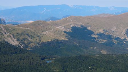 Le lac des Monges au milieu de la forêt avec au loin la montagne de Lure