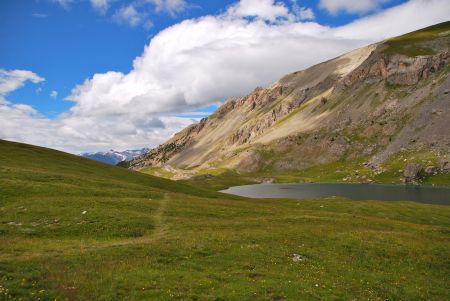 On distingue le sentier qui descend dans les gorges. Au fond, les premiers sommets enneigés des Écrins